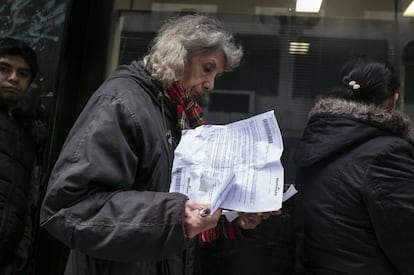 Una mujer espera en la fila para pagar su boleta mientras hace cuentas.