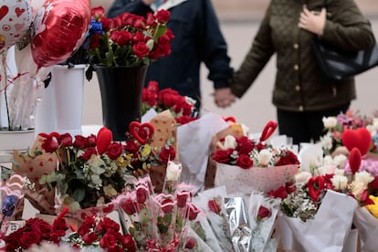 Una pareja pasea de la mano ante una floristería en Valencia.