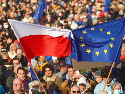 Vários manifestantes erguem bandeiras da Polôniaeda UE, em uma marcha no domingo emCracóvia.