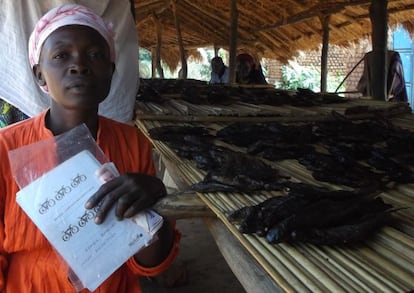 Una mujer con su micro negocio de pescado ahumado y con su libreta del préstamo detiene una bici para dirigirse a más mercados donde vender sus productos.