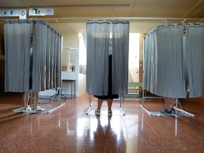 Tres votantes usan las cabinas electorales en un colegio de Granda, este 23 de julio.