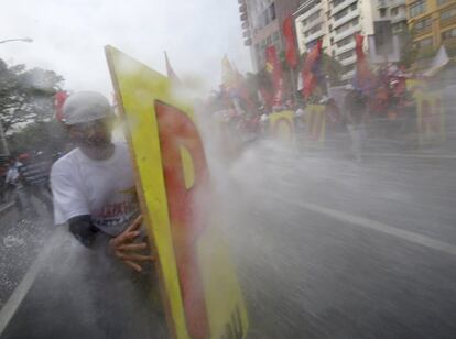 Un cañón de agua impide la llegada de un grupo de manifestantes a la embajada de EE UU en Manila (Filipinas), en protesta por la próxima visita del Obama.