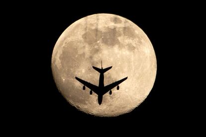 Un avión pasa frente a la superluna rosa, en la ciudad de Basora (Irak).