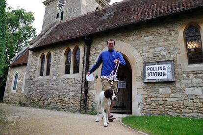 Un hombre acompañado de su perro sale de ejercer su derecho a voto en una iglesia empleada como centro electoral en Stadhampton,cerca de Oxford (Inglaterra).
