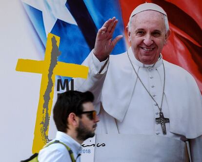 Un hombre camina frente a un póster con la imagen del papa Francisco, la ciudad se ha llenado de carteles de bienvenida al pontífice.