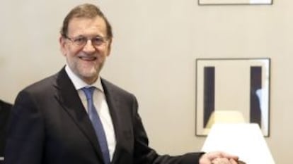 El presidente del Gobierno en funciones, Mariano Rajoy, posa con su maletín oficial tras formalizar su acta como diputado.