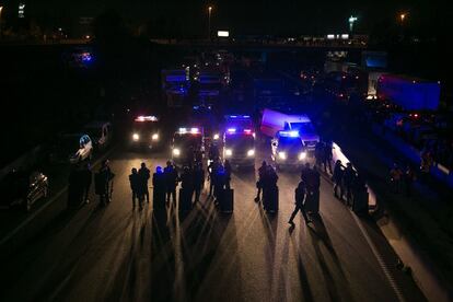 Miembros de la policía montan guardia mientras centenares de personas participan en el nuevo corte de la autopista AP-7, a la altura de Girona, que la plataforma Tusnami Democràtic ha convocado a partir de las seis de la tarde, una vez que la policía francesa y los Mossos d'Esquadra han logrado reabrir el paso por La Jonquera.