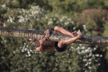 Un joven trata de sujetarse a la grasienta madera, algo imposible, debido al material empleado.