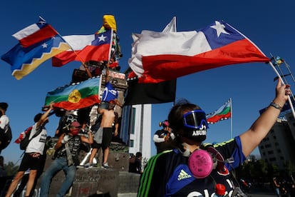 Manifestantes ondean banderas chilenas durante las protestas del estallido social, en 2019 en Santiago, Chile.