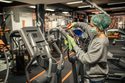 Funcionária faz limpeza dos equipamentos de uma academia.