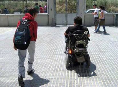 Aaron en silla de ruedas, acompañado por su primo, a la salida del instituto público Marjana de Chiva.