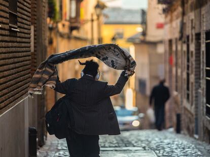 Una mujer se echa una prenda de abrigo sobre los hombros mientras camina por una calle de Toledo, el pasado lunes.