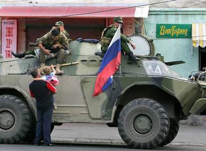 Un hombre y una niña surosetios hablan con un soldado ruso a bordo de un vehículo blindado en Tsjinvali.