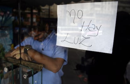 Un empleado, tras la puerta de un comercio cerrado en Caracas.