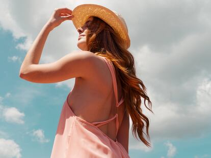 Chica tomando en sol con un sombrero.