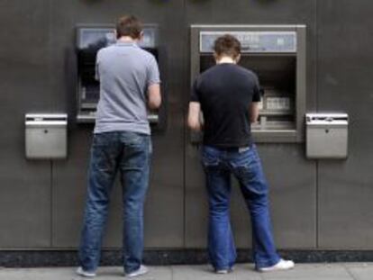 Dos clientes sacan dinero en sendos cajeros autom&aacute;ticos del Royal Bank of Scotland (RBS) en Londres.