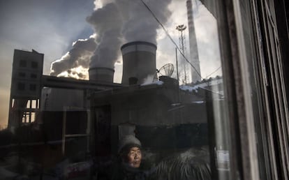 Un hombre en su casa, junto a una planta de carb&oacute;n en Shanxi (China).