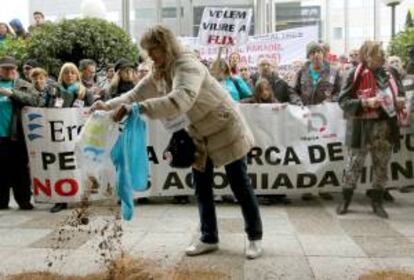 Una manifestante esparce tierra ante la sede de Ercros durante la protesta que protagonizan unas 800 personas de Flix (Tarragona) en Barcelona en contra los 156 despidos anunciados por la empresa química Ercros en la planta que tiene en esta población de las tierras del Ebro. EFE/Archivo