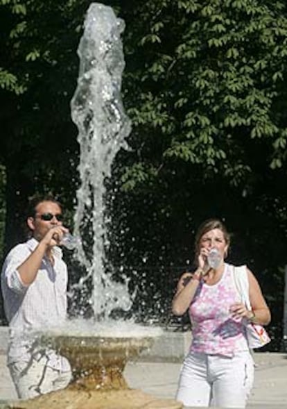 Dos visitantes del Retiro se refrescan con agua embotellada.