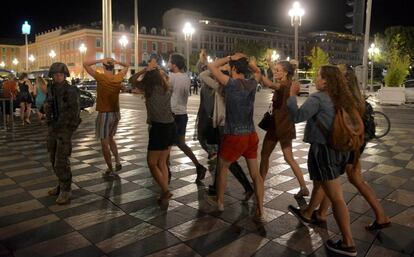 Un grup de persones creua un carrer de Niça, amb els braços al cap, després de l'atemptat terrorista.