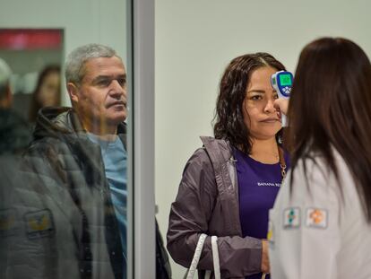 Personal sanitario toma la temperatura a los viajeros en el aeropuerto de Ciudad de México.