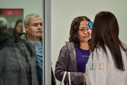 Personal sanitario toma la temperatura a los viajeros en el aeropuerto de Ciudad de México.