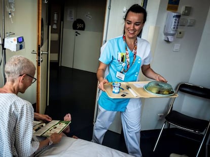 Una enfermera dispensa a un paciente comida elaborada con métodos tradicionales mientras este consulta una publicación.