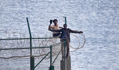 Dos de los inmigrnates encaramados en las valla del espigón de Benzú.