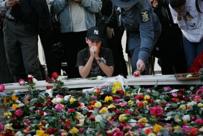 Un niño reza en la <i>zona cero,</i> en un lugar lleno de flores para homenajear a las víctimas de los atentados terroristas del 11 de septiembre de 2001.