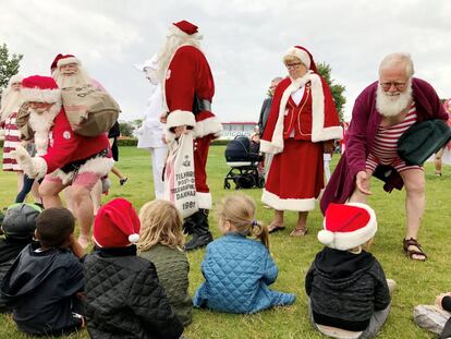 Santa Claus con atuendos veraniegos saludan a niños durante la celebración del congreso.