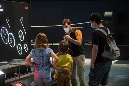 Un mediador de CosmoCaixa explica un experimento a unos visitantes, el lunes en la reapertura del museo.