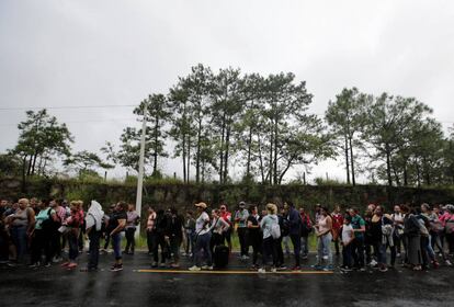 Migrantes hondureños hacen cola para cruzar a Guatemala en su camino a EE UU.