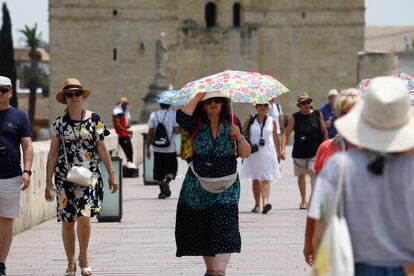 Varios turistas pasean protegiéndose del sol con sombreros y paraguas durante la ola de calor, en Córdoba.