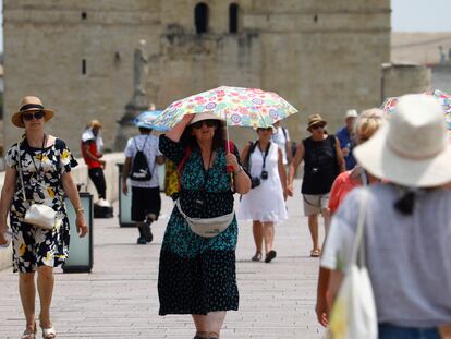 Varios turistas pasean protegiéndose del sol con sombreros y paraguas durante la ola de calor, en Córdoba.