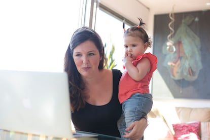 Eva Colera works with her baby in her arms.