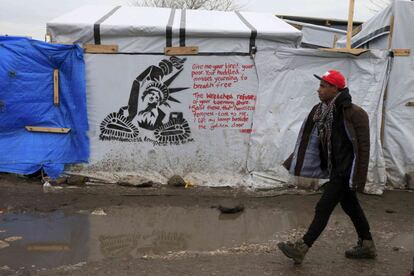 A migrant walks past a stencil graffiti with a statue of liberty and the message, "Send the Homless, Tempest tost to me", in the southern part of a camp for migrants called the "jungle", in Calais, northern France, February 23, 2016. French authorities have asked migrants living in tents and makeshift shelters in the southern sector of the "jungle", to evacuate the area. REUTERS/Pascal Rossignol 