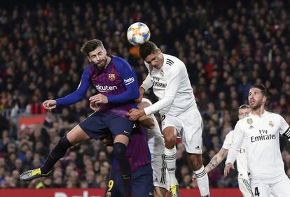 Gerard Piqué intenta tocar de cabeza un balón alto junto al defensa del Real Madrid Raphael Varane.