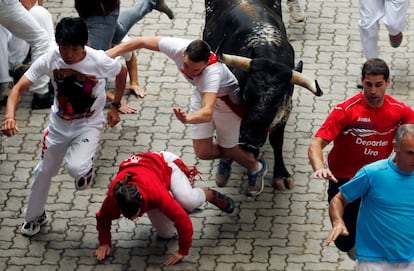 Unos corredores se caen delante de un toro de Victoriano del Río durante el sexto encierro de Sanfermín. 