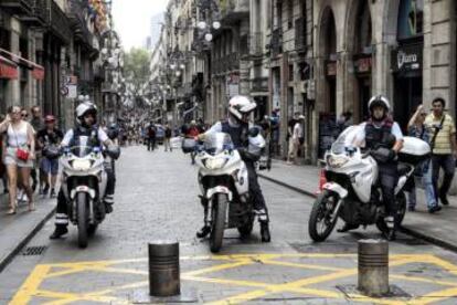 Three regional police officers block the entrance to a street near the La Rambla boulevard.