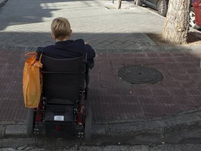 Una mujer en silla de ruedas sube un bordillo en una calle de Madrid. 