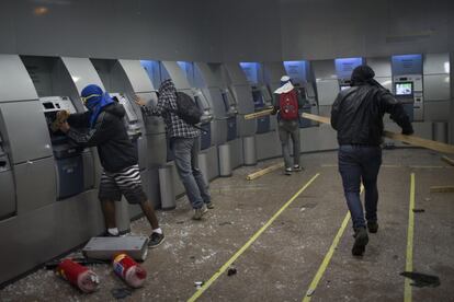 Unos encapuchados aprovechan la protesta de apoyo a los profesores brasileños para asaltar unos cajeros automáticos de una sucursal bancaria en Río de Janeiro (Brasil), 8 de octubre de 2013. Los profesores que lideraban la manifestación optaron por ponerle fin a su marcha y abandonar la Cinelandia por no estar de acuerdo con los actos violentos.