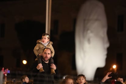 Un hombre sostiene a un niño a hombros durante la cabalgata de Reyes Magos en Madrid.