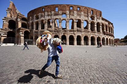 Un vendedor ambulante intenta atraer a los pocos turistas que pasan cerca del Coliseo, en Roma (Italia).