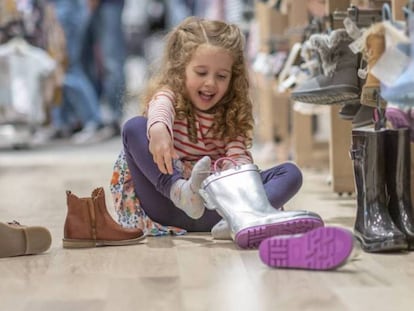 Una niña se prueba zapatos en una tienda. 