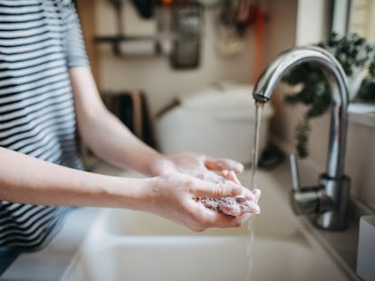 Una mujer se lava las manos con jabón en el fregadero.