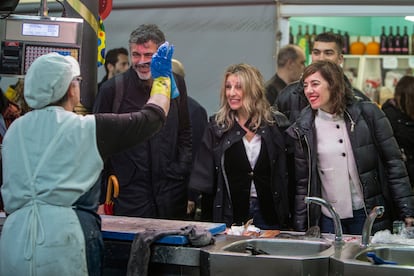 La vicepresidenta del Gobierno y líder de Sumar, Yolanda Díaz (centro) y la candidata de Sumar a la Presidencia de la Xunta de Galicia, Marta Lois (derecha), visitan un puesto en el mercado de Cangas de Morrazo, el 9 de febrero en Pontevedra. 
