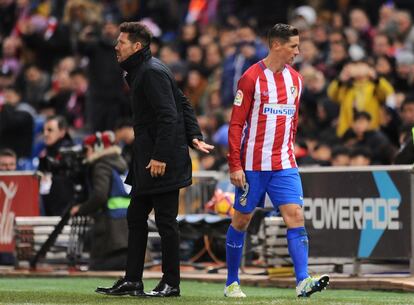 Fernando Torres pasa delante de Diego Simeone, tras ser cambiado.