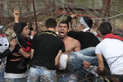 Refugiados palestinos llevan a un hombre que resultó herido en Marun el Ras, una localidad libanesa fronteriza con Israel.