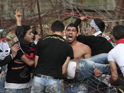 Refugiados palestinos llevan a un hombre que resultó herido en Marun el Ras, una localidad libanesa fronteriza con Israel.
