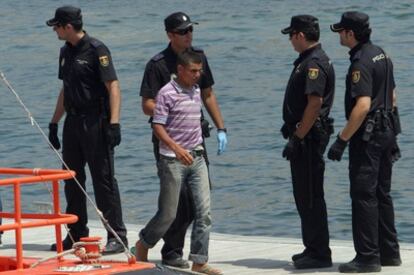 Agentes de la Policía Nacional junto a uno de los inmigrantes que han llegado hoy en patera a Alicante.